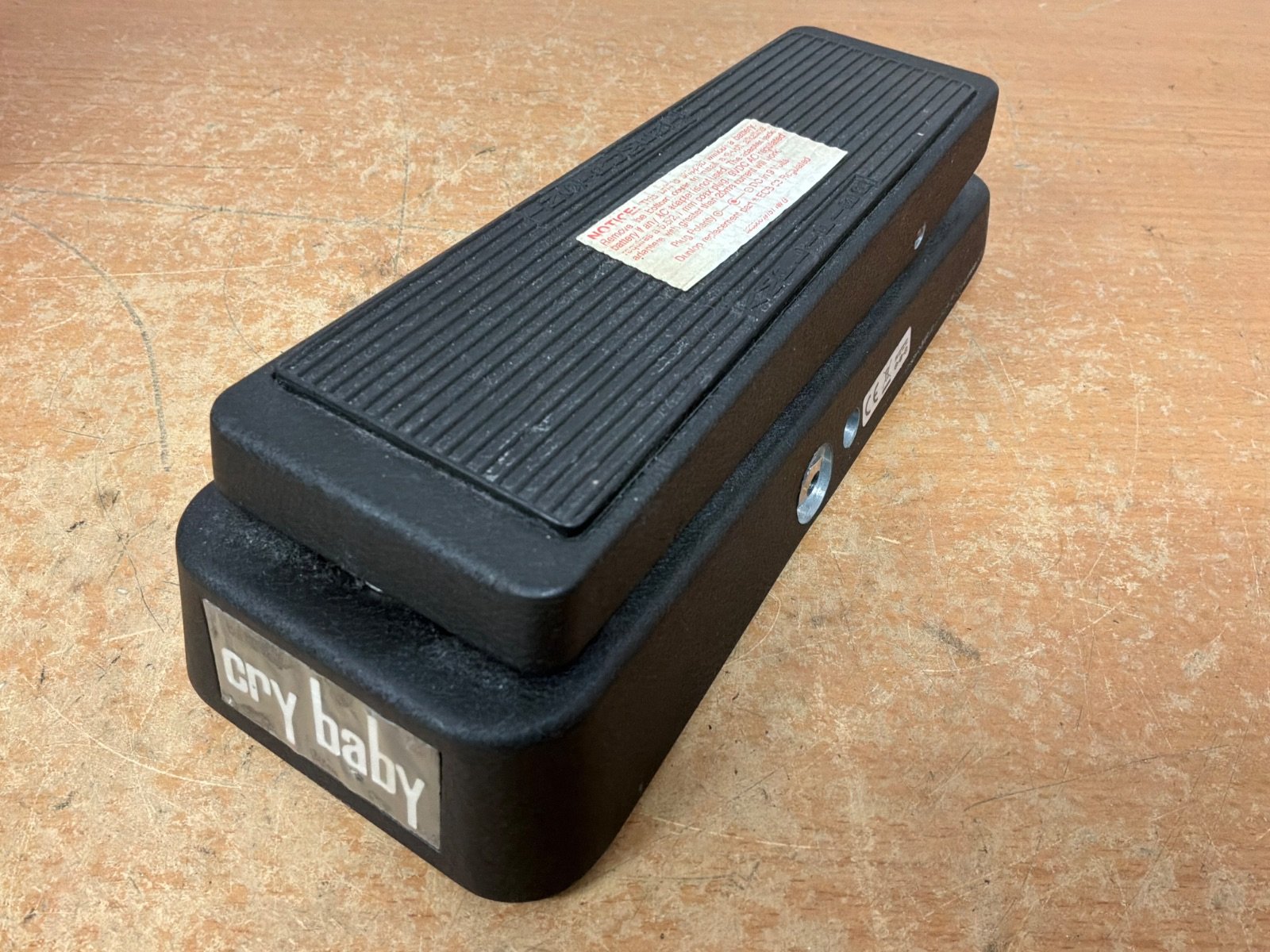 Dunlop Cry Baby Wah guitar effects pedal in used condition, missing power supply and battery flap, with visible wear on the surface.