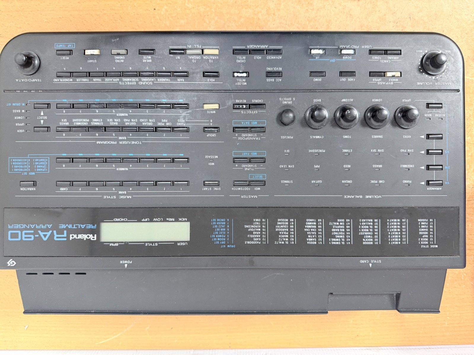 A vintage Roland RA-90 Realtime Arranger Keyboard Synthesizer in used condition, featuring various knobs and buttons on a black surface.