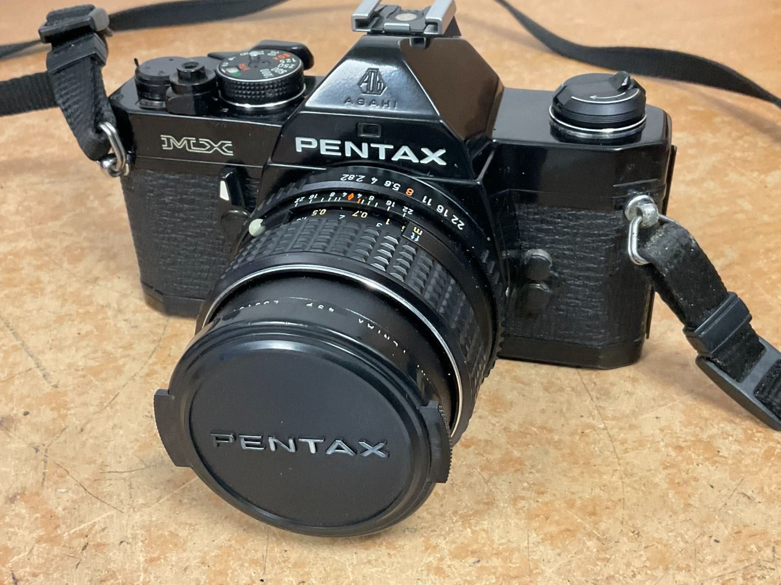 Pentax MX 35mm SLR camera with SMC Pentax-M 28mm f/2 lens, in good vintage condition, featuring a black body and lens cap.